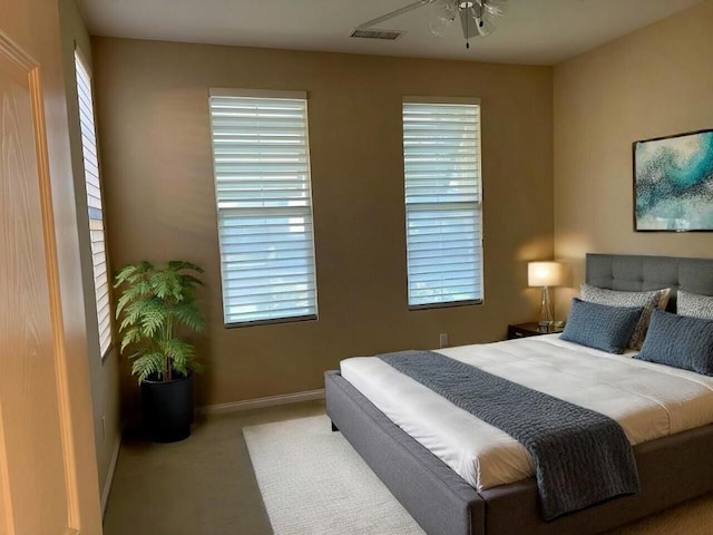 bedroom featuring ceiling fan, light colored carpet, and multiple windows