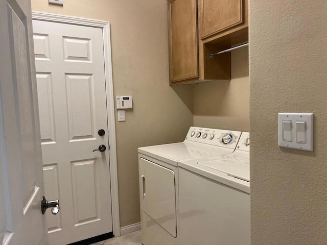 laundry room with light tile patterned flooring, cabinets, and washer and dryer