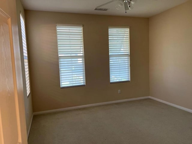 carpeted empty room featuring ceiling fan and plenty of natural light