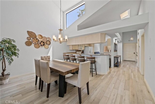 324 Sundance Cir, Palm Desert, CA 92211 - dining area with light wood-type flooring, high vaulted ceiling, and a chandelier