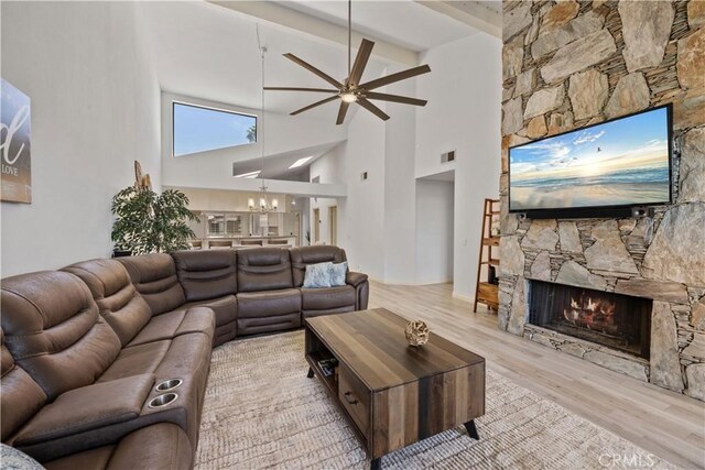 324 Sundance Cir, Palm Desert, CA 92211 - living room featuring beam ceiling, a stone fireplace, light hardwood / wood-style flooring, high vaulted ceiling, and ceiling fan with notable chandelier