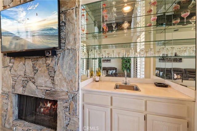 324 Sundance Cir, Palm Desert, CA 92211 - bar featuring a fireplace, white cabinetry, and sink