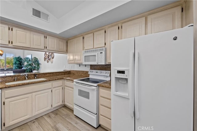 324 Sundance Cir, Palm Desert, CA 92211 - kitchen with white appliances, sink, light hardwood / wood-style flooring, vaulted ceiling, and dark stone countertops