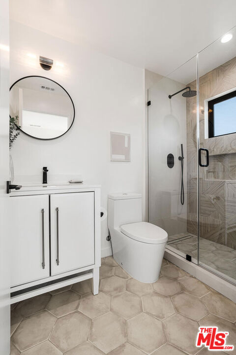 bathroom with tile patterned floors, vanity, toilet, and a shower with door