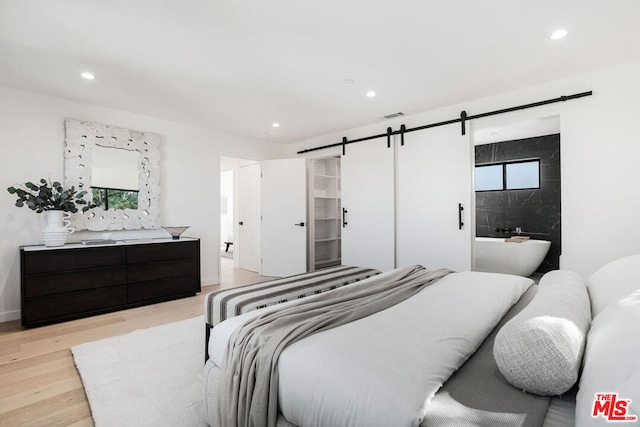 bedroom featuring a barn door and light hardwood / wood-style floors