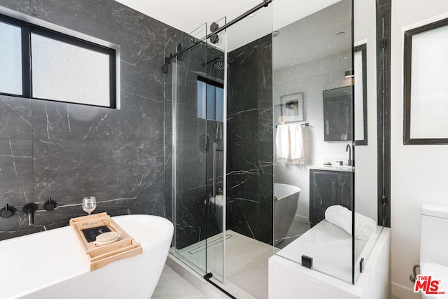 bathroom featuring separate shower and tub, vanity, and tile walls