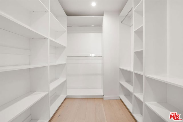 walk in closet with light hardwood / wood-style floors