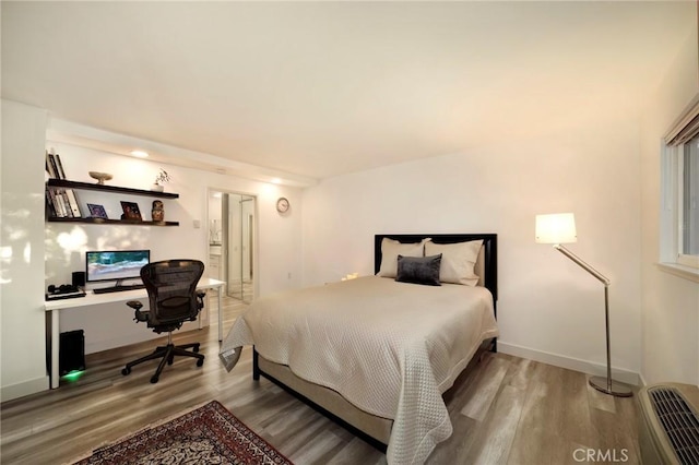 bedroom featuring built in study area, baseboards, and wood finished floors