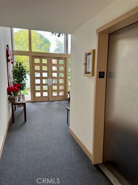 doorway featuring elevator, a wealth of natural light, french doors, and carpet floors