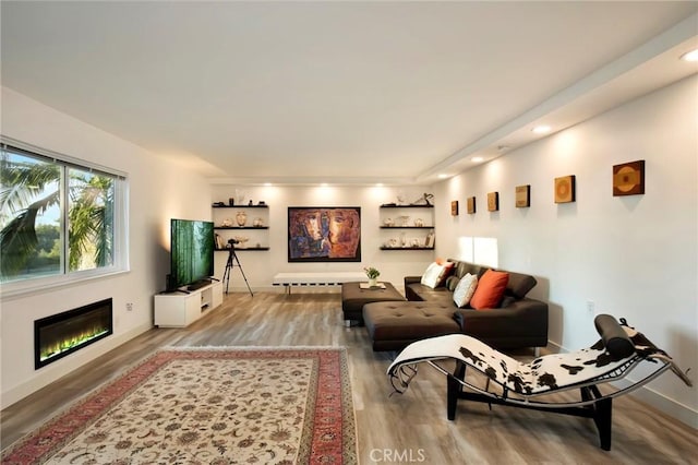 living area featuring a glass covered fireplace, recessed lighting, wood finished floors, and baseboards