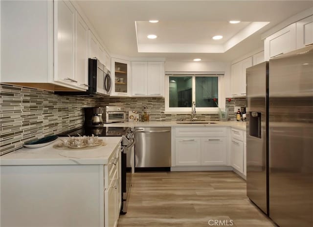 kitchen with white cabinets, a raised ceiling, sink, and appliances with stainless steel finishes