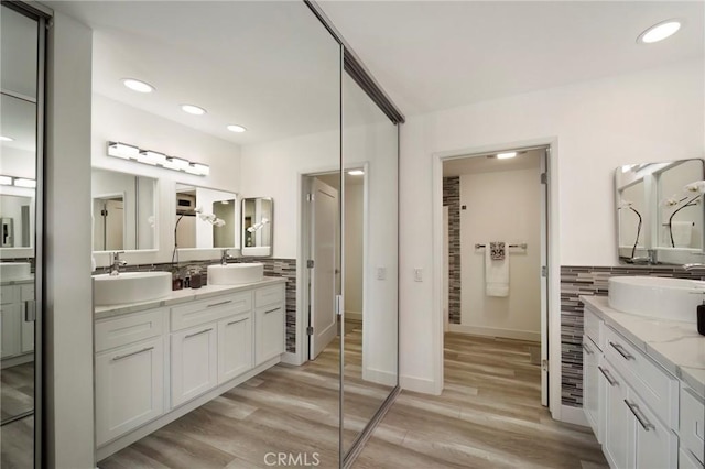 full bathroom with vanity, wood finished floors, baseboards, recessed lighting, and tasteful backsplash