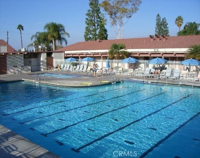 community pool with a patio and fence