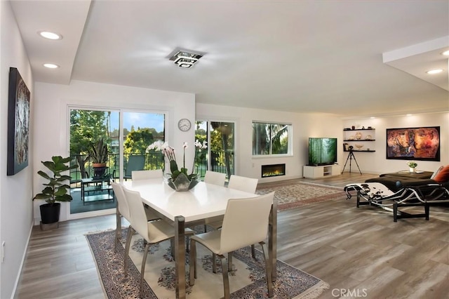 dining area with recessed lighting, wood finished floors, baseboards, and a warm lit fireplace