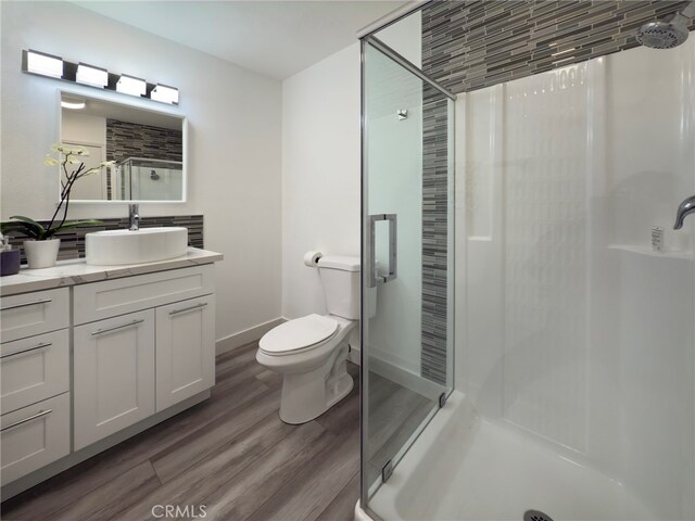 bathroom with a shower, hardwood / wood-style floors, vanity, and toilet