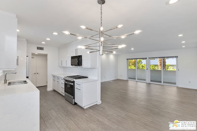 kitchen featuring sink, hanging light fixtures, light hardwood / wood-style floors, white cabinetry, and gas stove