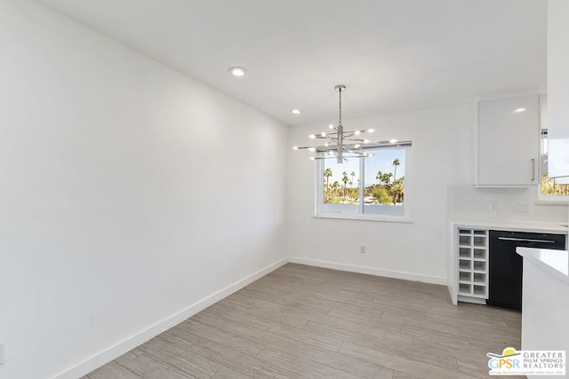 unfurnished dining area with plenty of natural light, an inviting chandelier, and light wood-type flooring