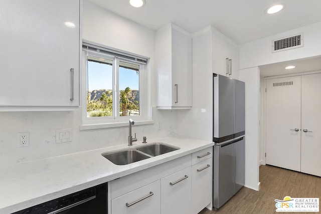 kitchen with stainless steel fridge, sink, light hardwood / wood-style flooring, dishwasher, and white cabinets