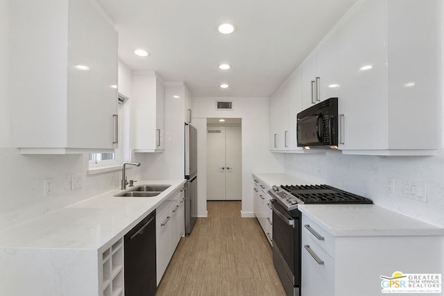 kitchen with light wood-type flooring, sink, white cabinetry, and black appliances