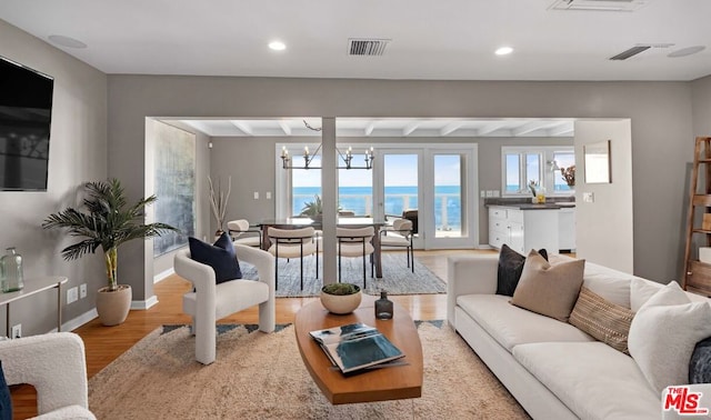 living room with a water view, light hardwood / wood-style floors, and a notable chandelier