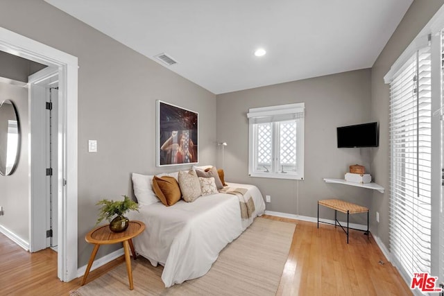 bedroom with light hardwood / wood-style flooring and multiple windows