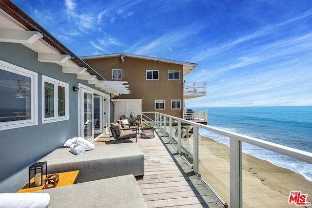 balcony featuring a water view and a beach view