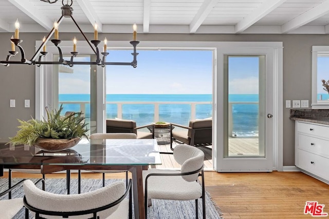 sunroom / solarium featuring beam ceiling, a wealth of natural light, and a water view