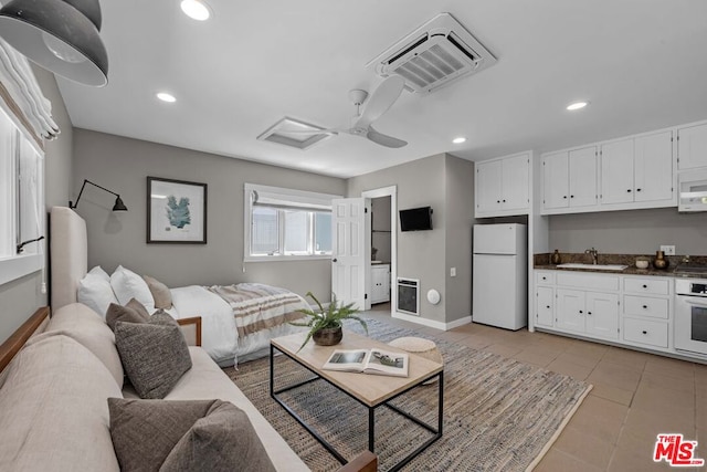 tiled living room with ceiling fan and sink