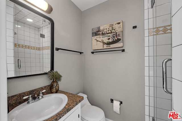 bathroom with a shower with door, vanity, and toilet