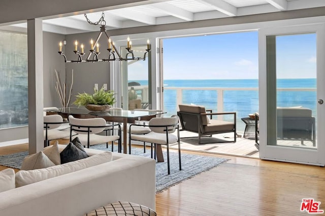 sunroom with beamed ceiling, a water view, and an inviting chandelier