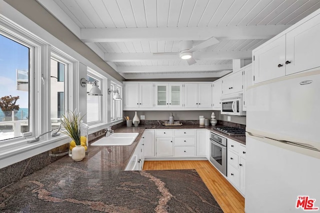 kitchen featuring sink, light hardwood / wood-style flooring, appliances with stainless steel finishes, beam ceiling, and white cabinetry