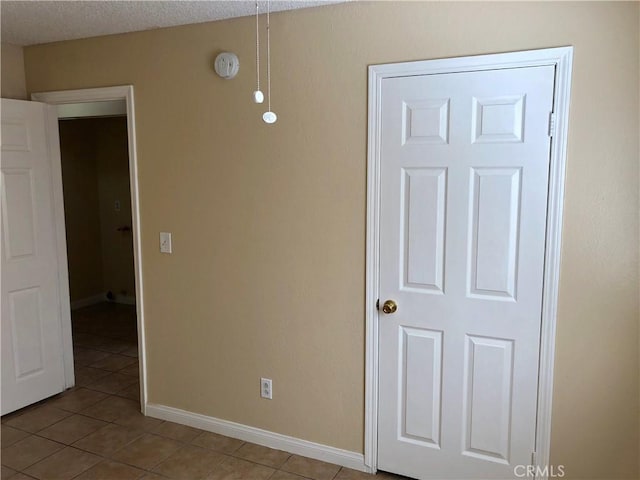 empty room with light tile patterned floors and a textured ceiling