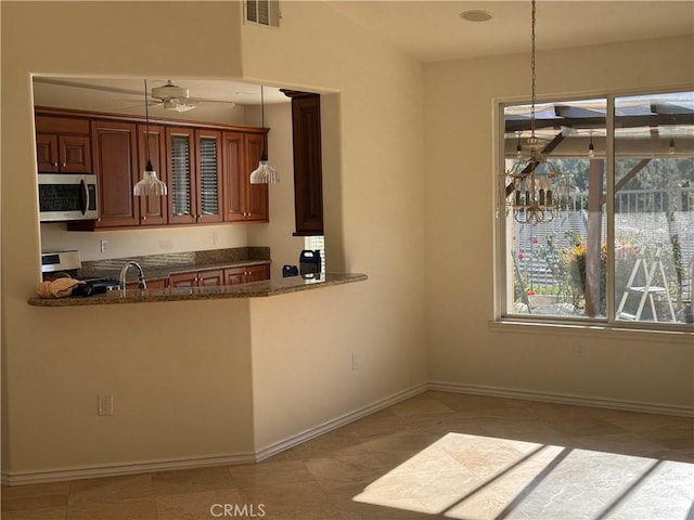 kitchen with kitchen peninsula, ceiling fan, electric stove, pendant lighting, and dark stone countertops