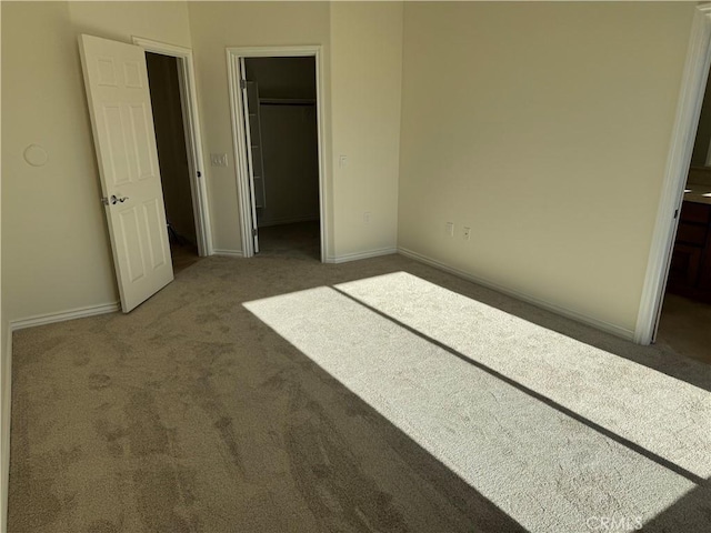 unfurnished bedroom featuring dark carpet, a spacious closet, and a closet