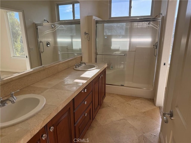 bathroom with vanity, a shower with shower door, and a wealth of natural light