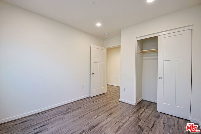 unfurnished bedroom featuring light wood-type flooring and a closet