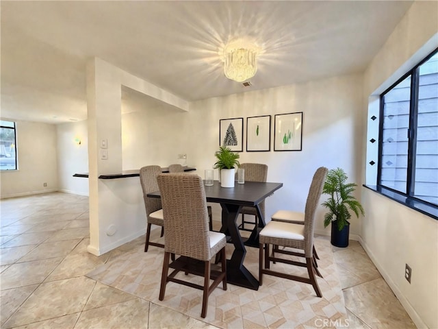 dining room featuring a notable chandelier, a healthy amount of sunlight, and light tile patterned flooring