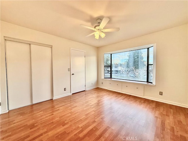 unfurnished bedroom featuring ceiling fan, light hardwood / wood-style flooring, and two closets