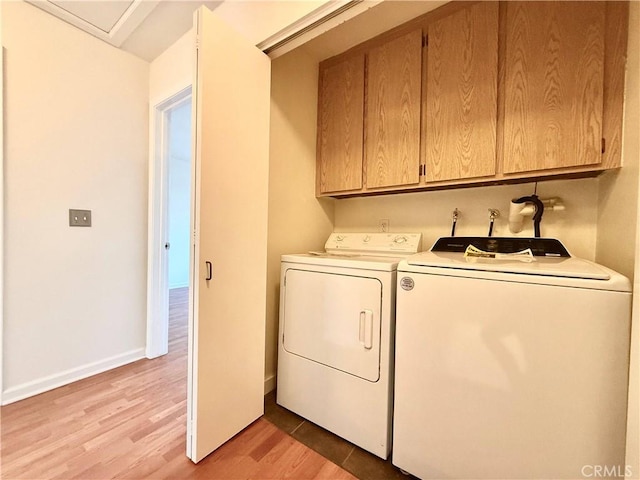 laundry area with cabinets, light wood-type flooring, and washer and dryer