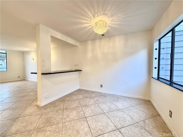 unfurnished room featuring light tile patterned floors, an inviting chandelier, and plenty of natural light