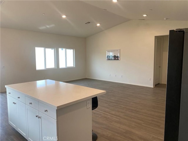 kitchen with dark hardwood / wood-style flooring, a center island, white cabinetry, and lofted ceiling