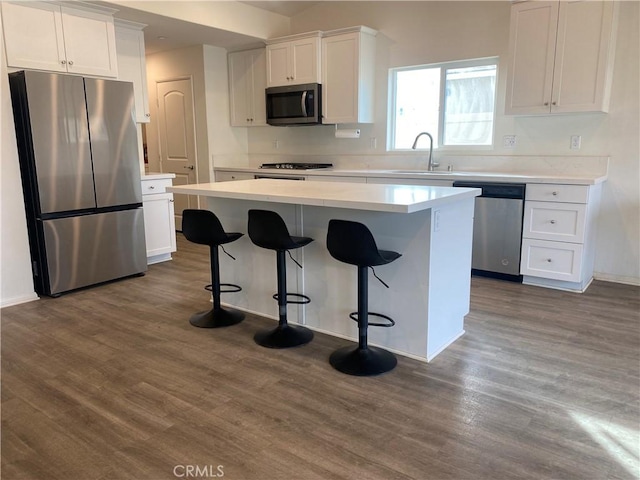 kitchen with white cabinets, appliances with stainless steel finishes, dark hardwood / wood-style floors, and a kitchen island