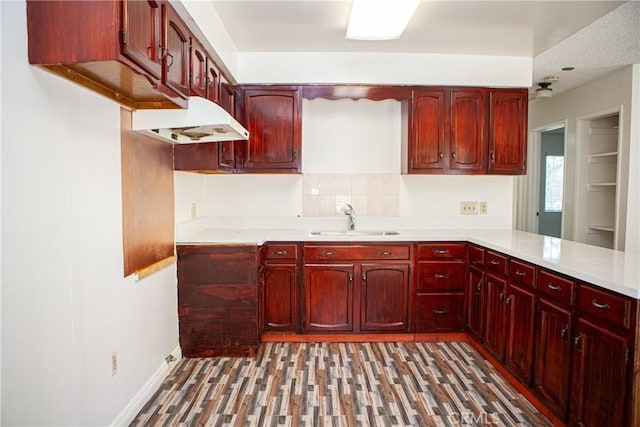 kitchen featuring a textured ceiling, kitchen peninsula, sink, and dark wood-type flooring