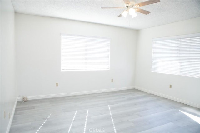 unfurnished room with ceiling fan, light hardwood / wood-style floors, a textured ceiling, and a wealth of natural light