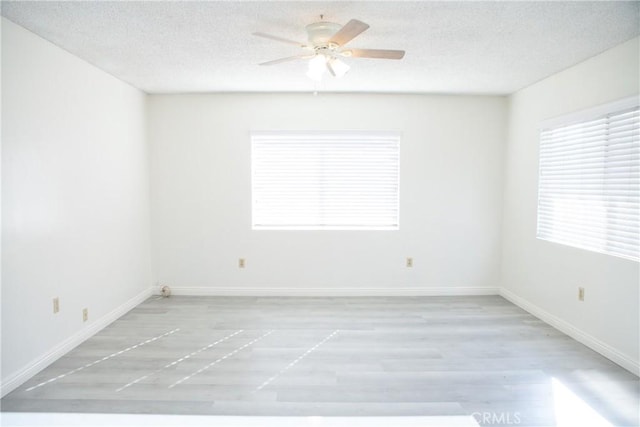 unfurnished room with ceiling fan, a textured ceiling, and light wood-type flooring