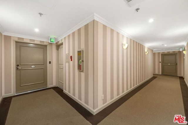 hall with ornamental molding and dark colored carpet