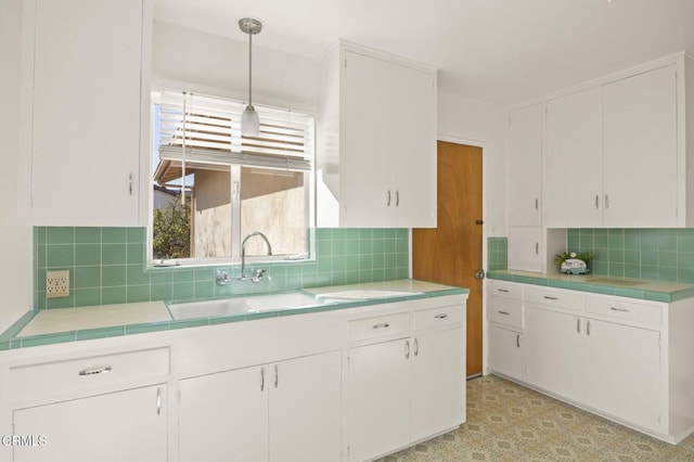 kitchen featuring white cabinets, decorative backsplash, hanging light fixtures, and sink