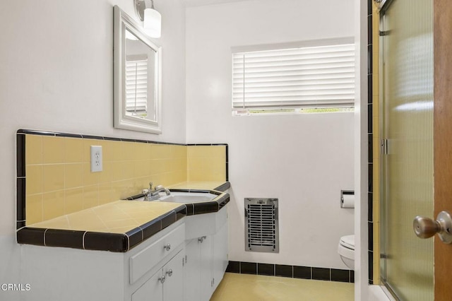 bathroom featuring vanity, toilet, a shower with shower door, and tasteful backsplash