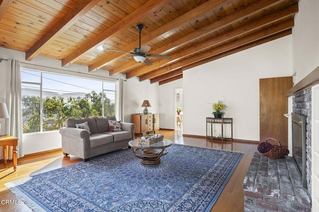 living area with vaulted ceiling with beams, a fireplace, wood ceiling, wood finished floors, and baseboards