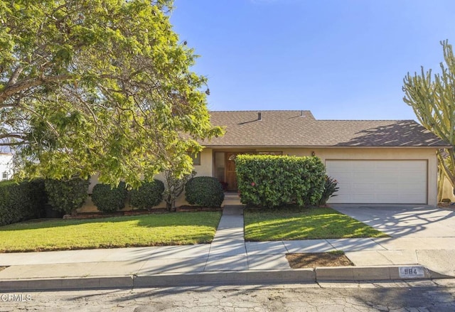 obstructed view of property with a garage, concrete driveway, roof with shingles, stucco siding, and a front lawn